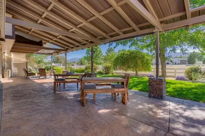 an outdoor patio with benches and tables and a roof at Marbella Lane - Eccentric 4BR Modern Ranch Home in Reno
