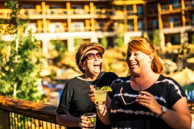 two women standing next to each other holding drinks at Rush Creek Lodge at Yosemite in Groveland