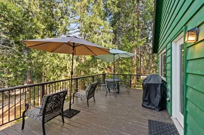 a deck with chairs and a table and an umbrella at Blue Meadow-Family Pet Friendly & near the lake in Shaver Lake