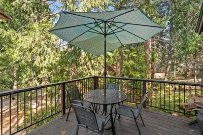 a table and chairs with an umbrella on a deck at Blue Meadow-Family Pet Friendly & near the lake in Shaver Lake