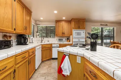 a kitchen with wooden cabinets and white appliances at Rustic Pines- Family Fun Game Cabin in East Village in Shaver Lake