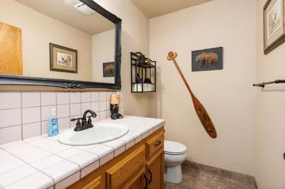 a bathroom with a sink and a toilet and a mirror at Rustic Pines- Family Fun Game Cabin in East Village in Shaver Lake