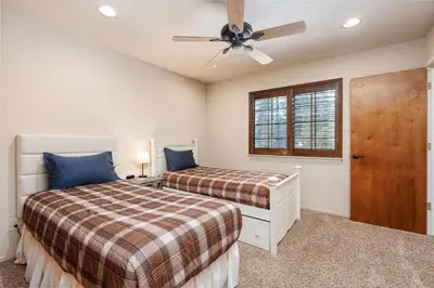 a bedroom with two beds and a ceiling fan at Rustic Pines- Family Fun Game Cabin in East Village in Shaver Lake