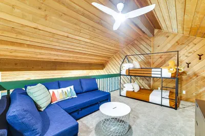 a living room with a blue couch and a bed at 2 Mi to Eagle Lodge! Multi-Level Haven with Hot Tub in Mammoth Lakes
