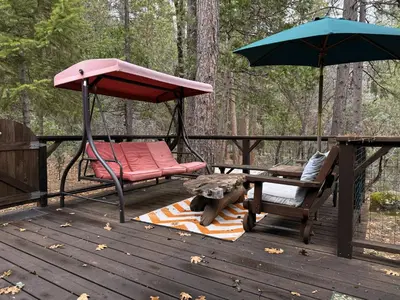 a swing and a chair and an umbrella on a deck at 45R Camp Duke in North Wawona