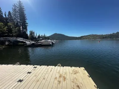 a dock on a lake with boats in the water at Boat Dock - Lake Front - Dog Friendly - Sleeps 7 in Bass Lake