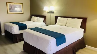 two beds in a hotel room with white and blue sheets at Rodeway Inn Jackson in Jackson
