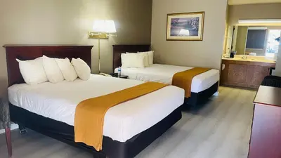 a hotel room with two beds and a mirror at Rodeway Inn Jackson in Jackson