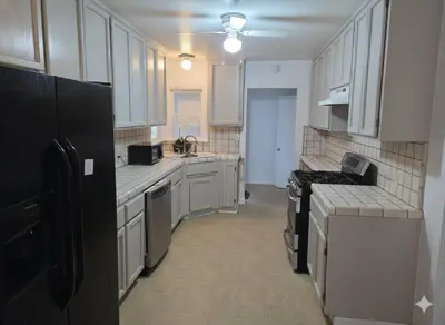 a kitchen with white cabinets and a black refrigerator at 3BR 2B Boho Retreat with meditation room in Modesto