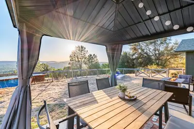 a patio with a wooden table and chairs at Cold Plunge, Hot Tub, Firepit, BBQ, Pet-Friendly, Sunset Views near Yosemite in Coarsegold