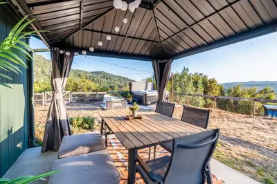 an outdoor patio with a wooden table and chairs at Cold Plunge, Hot Tub, Firepit, BBQ, Pet-Friendly, Sunset Views near Yosemite in Coarsegold