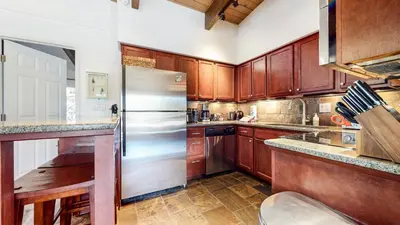 a kitchen with wooden cabinets and a stainless steel refrigerator at Chateau Doex #8 condo in Mammoth Lakes