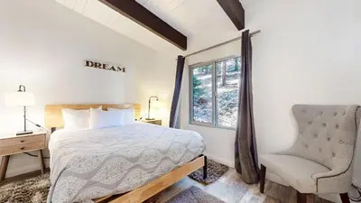 a bedroom with a bed and a chair and a window at Chateau Doex #8 condo in Mammoth Lakes