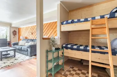 a bedroom with bunk beds and a living room with a couch at Discovery Four 109 in Mammoth Lakes