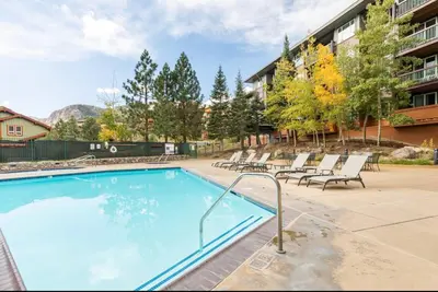 a large swimming pool with lounge chairs next to a building at Juniper Springs Lodge 437 in Mammoth Lakes