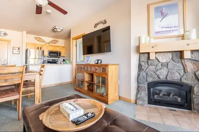 a living room with a stone fireplace and a table at Juniper Springs Lodge 437 in Mammoth Lakes