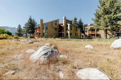 a building in a field with rocks in front of it at Mammoth Creek 29 in Mammoth Lakes
