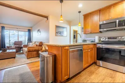 a kitchen with wooden cabinets and a living room at Chamonix 17 in Mammoth Lakes