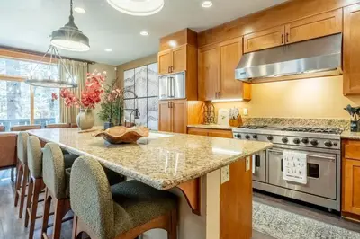 a kitchen with wooden cabinets and a large island with bar chairs at Timbers 1031 in Mammoth Lakes