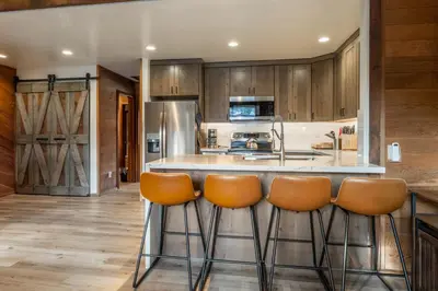a kitchen with wooden cabinets and a bar with stools at Canyon Ski and Racquet 3 in Mammoth Lakes