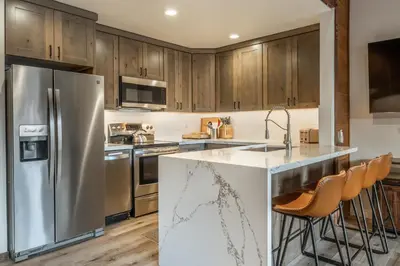 a kitchen with wooden cabinets and a stainless steel refrigerator at Canyon Ski and Racquet 3 in Mammoth Lakes