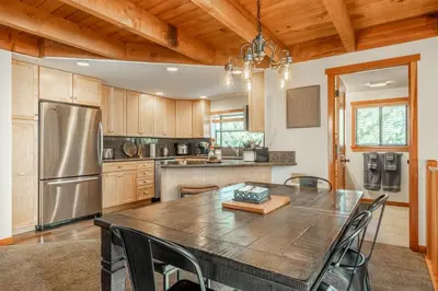 a kitchen with a large wooden table and stainless steel refrigerator at Snowflower 21 in Mammoth Lakes
