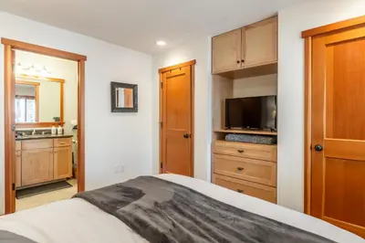 a bedroom with a bed and a tv and a cabinet at Snowflower 21 in Mammoth Lakes