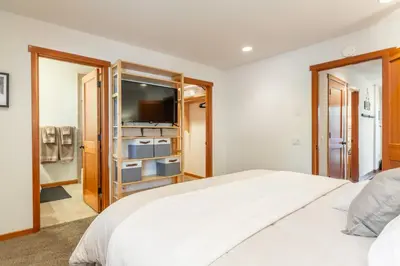a bedroom with a large white bed and a television at Snowflower 21 in Mammoth Lakes