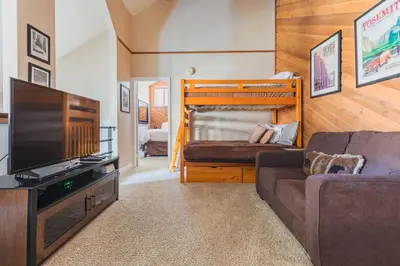 a living room with a couch and a tv and a bed at Aspen Creek 219 in Mammoth Lakes