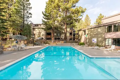 a swimming pool with chairs and a building at Summit 43 in Mammoth Lakes