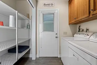 a white kitchen with a sink and a door at Whispering Pines in Oakhurst