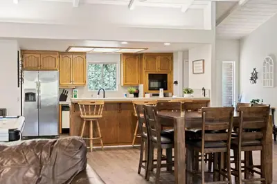 a kitchen with wooden cabinets and a table and chairs at Whispering Pines in Oakhurst