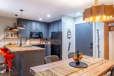a kitchen with a wooden table and a refrigerator at Ski In Canyon Lodge Modern 1 bdrm Pacman and Garage in Mammoth Lakes