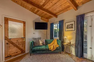 a living room with a green couch and a door at 16 mi to Yosemite - Rustic Studio - Hiking Nearby in Oakhurst