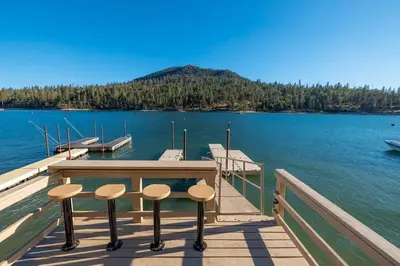 a dock with two stools and a table on the water at Lake View Private Dock 18 miles to Yosemite in Bass Lake