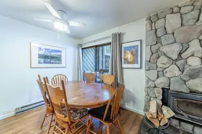 a dining room with a table and a stone fireplace at Adventure by Day Cozy Nights Family Alpine Condo in Mammoth Lakes