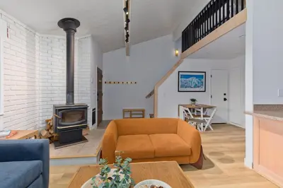 a living room with a couch and a wood stove at Stylish Mammoth 1BR & Loft With Fireplace in Mammoth Lakes
