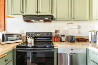 a kitchen with green cabinets and a stove top oven at Val DIsere 27 in Mammoth Lakes