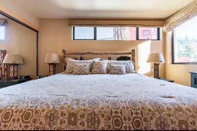 a bedroom with a large bed and two windows at Treehouse at Canyon Lodge Walk to Slopes in Mammoth Lakes