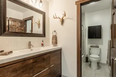 a bathroom with a sink and a toilet and a mirror at Summit 107 in Mammoth Lakes