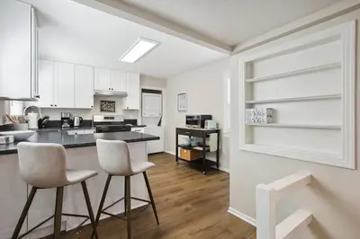 a kitchen with white cabinets and two bar stools at Pet-Friendly Private Cottage In Tahoe Park in Sacramento