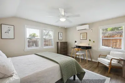 a bedroom with a bed and a desk and windows at Pet-Friendly Private Cottage In Tahoe Park in Sacramento