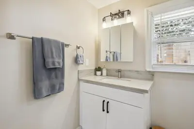 a white bathroom with a sink and a window at Pet-Friendly Private Cottage In Tahoe Park in Sacramento