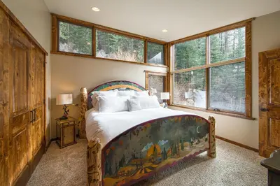 a bedroom with a bed in a room with windows at Painted River Retreat by Tahoe Getaways - 4BR w River Views, Hot Tub & EV Charger. in Truckee