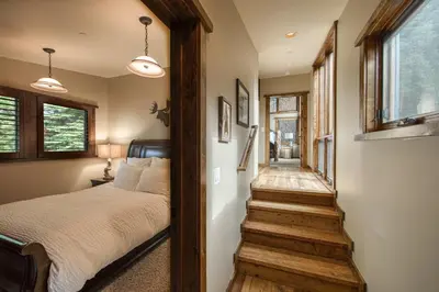 a bedroom with a bed and a stairway at Painted River Retreat by Tahoe Getaways - 4BR w River Views, Hot Tub & EV Charger. in Truckee