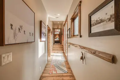 a hallway with pictures on the walls and a rug on the floor at Painted River Retreat by Tahoe Getaways - 4BR w River Views, Hot Tub & EV Charger. in Truckee