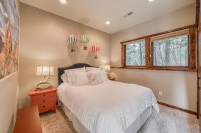 a bedroom with a bed and a window at Painted River Retreat by Tahoe Getaways - 4BR w River Views, Hot Tub & EV Charger. in Truckee