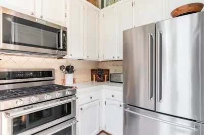 a kitchen with white cabinets and a stainless steel refrigerator at Chateau Sans Nom 30 in Mammoth Lakes