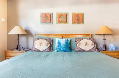 a bedroom with a bed with blue sheets and two lamps at Alpine Glow Escape Big Windows & Views! in Mammoth Lakes