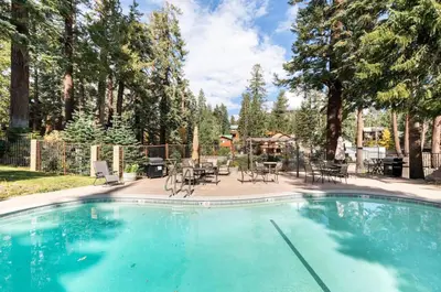 a swimming pool with chairs and tables and trees at Seasons Four 110 in Mammoth Lakes